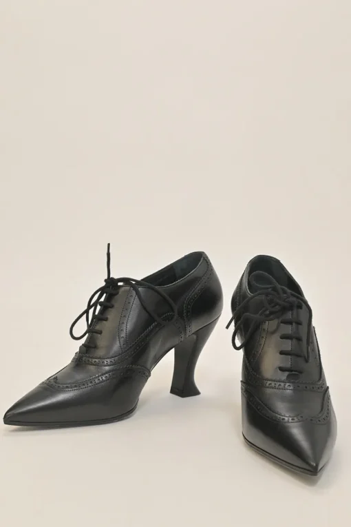 Black brogued leather pointed-toe lace-up Victorian-style heeled booties with metallic Coco Mark heel plaque appliqué