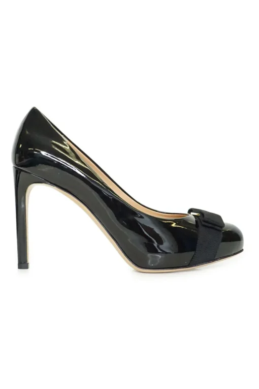 Black patent platform pumps with grosgrain Vara bow wrapped in brand's signature engraved metal plaque