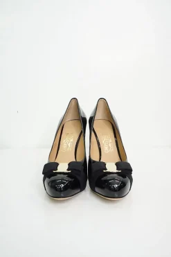 Black patent platform pumps with grosgrain Vara bow wrapped in brand's signature engraved metal plaque
