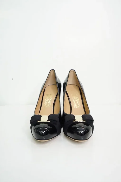 Black patent platform pumps with grosgrain Vara bow wrapped in brand's signature engraved metal plaque