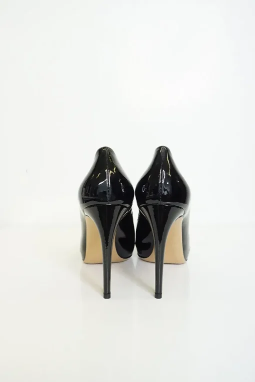 Black patent platform pumps with grosgrain Vara bow wrapped in brand's signature engraved metal plaque