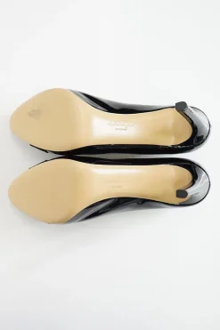 Black patent platform pumps with grosgrain Vara bow wrapped in brand's signature engraved metal plaque