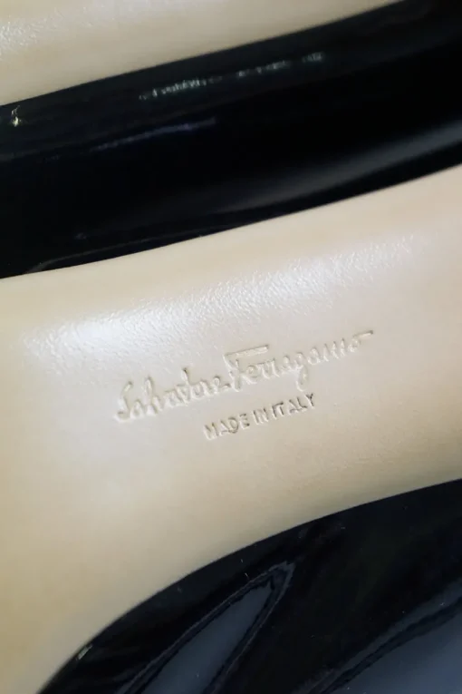 Black patent platform pumps with grosgrain Vara bow wrapped in brand's signature engraved metal plaque