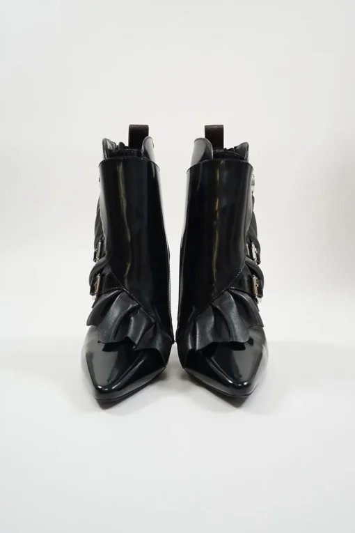 Black polished calfskin and leather pointed toe monk strap-style zip-up ankle booties with ruffle trim