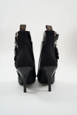 Black polished calfskin and leather pointed toe monk strap-style zip-up ankle booties with ruffle trim