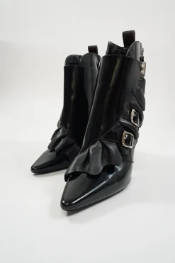 Black polished calfskin and leather pointed toe monk strap-style zip-up ankle booties with ruffle trim