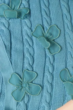 Blue cotton cable-knit button-front cardigan with flounce cuffs and tonal floral appliqués