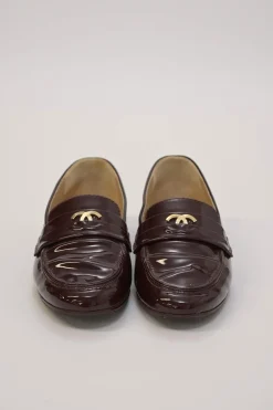 Brown patent leather round-toe slip-on penny loafers with gold-tone metallic Coco Mark vamp appliqué