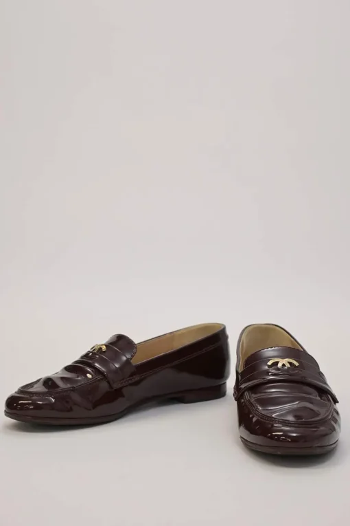 Brown patent leather round-toe slip-on penny loafers with gold-tone metallic Coco Mark vamp appliqué