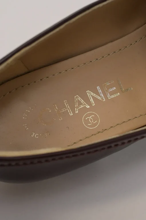 Brown patent leather round-toe slip-on penny loafers with gold-tone metallic Coco Mark vamp appliqué