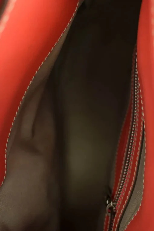 Coral leather satchel bag with visible top stitch and shoulder strap.