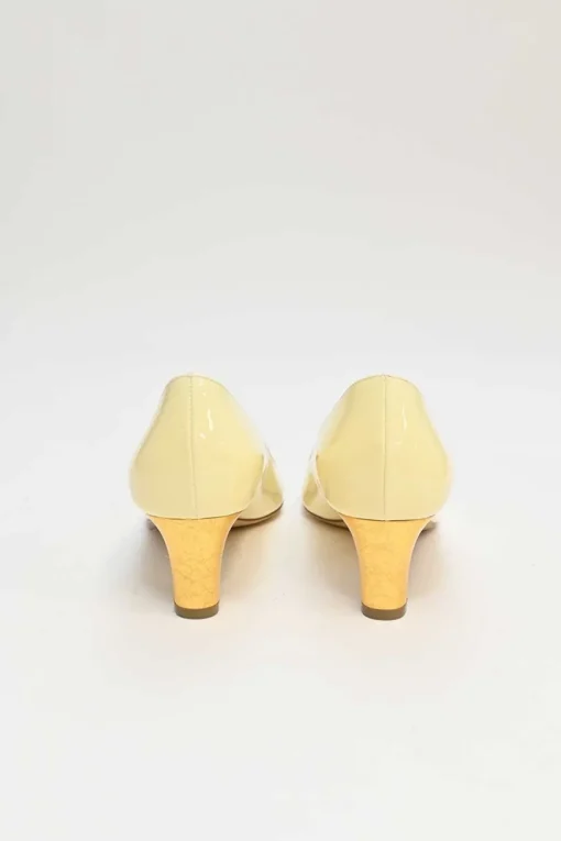 Cream patent leather almond-toe court pumps with signature pebble vamp buckle