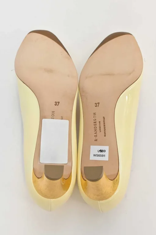 Cream patent leather almond-toe court pumps with signature pebble vamp buckle