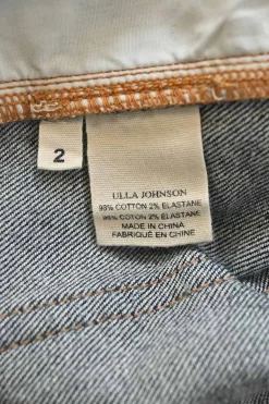Dark indigo cotton denim pull-on high-rise bow leg jeans with exposed button fly fastening