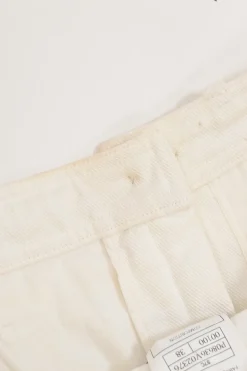 Ecru cotton denim pull-on high-rise skinny jeans with Coco Mark shank button appliqué along cuffs
