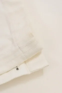 Ecru cotton denim pull-on high-rise skinny jeans with Coco Mark shank button appliqué along cuffs