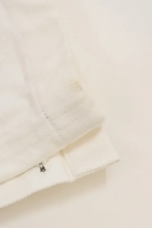Ecru cotton denim pull-on high-rise skinny jeans with Coco Mark shank button appliqué along cuffs