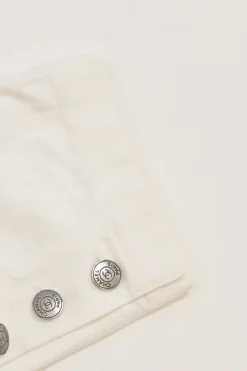 Ecru cotton denim pull-on high-rise skinny jeans with Coco Mark shank button appliqué along cuffs