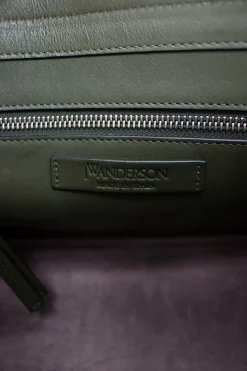 Green and brown leather top satchel bag with silver metal detail on the fabric flap and detachable fabric shoulder strap.