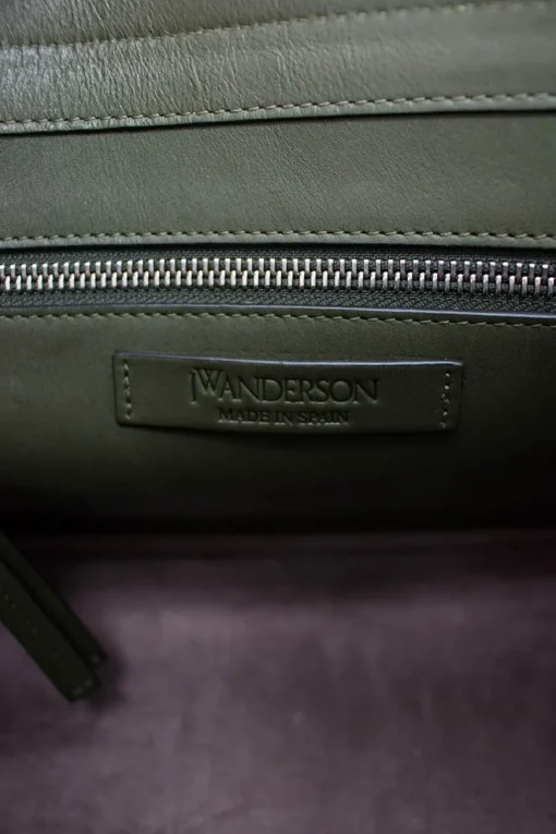 Green and brown leather top satchel bag with silver metal detail on the fabric flap and detachable fabric shoulder strap.