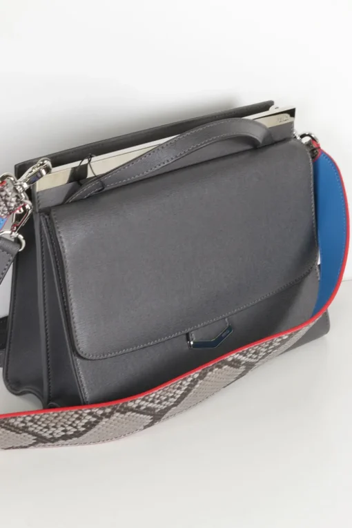 Grey pebbled leather bag with front flap, magnetic clasp and short top handle.
