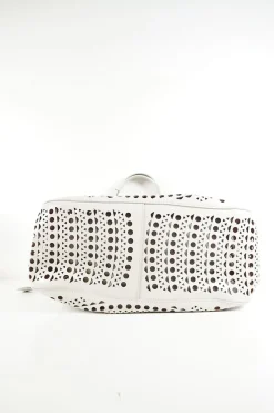Grey perforated leather top handle bag. Drawstring closure. Bag comes with detachable leather zip pouch