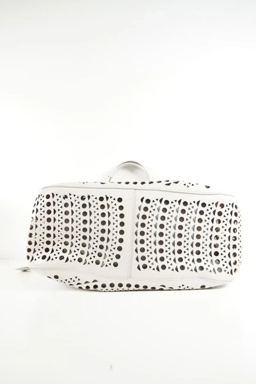 Grey perforated leather top handle bag. Drawstring closure. Bag comes with detachable leather zip pouch
