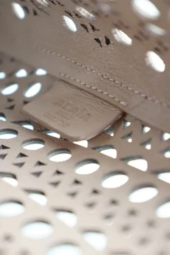 Grey perforated leather top handle bag. Drawstring closure. Bag comes with detachable leather zip pouch