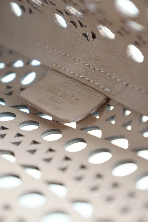 Grey perforated leather top handle bag. Drawstring closure. Bag comes with detachable leather zip pouch
