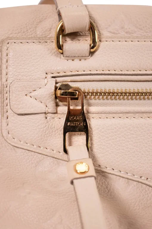 Louis Vuitton Empreinte monogram embossed calf leather bag in cream colour with zip closure. Rectangular shape with 2 shoulder straps. Bag has one external zipped pocket. Interior is fabric lined, with two side pockets, and a third on front panel. Gold toned hardware.