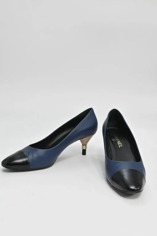 Navy and black contrast leather almond-toe pumps with patterned gold-tone metal heels and black Coco logo on ankle counter