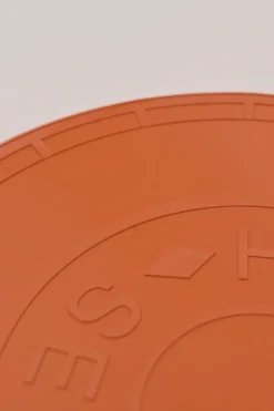 Orange plastic Wouf flying disc featuring 'Hermès Sellier Paris' embossed detail