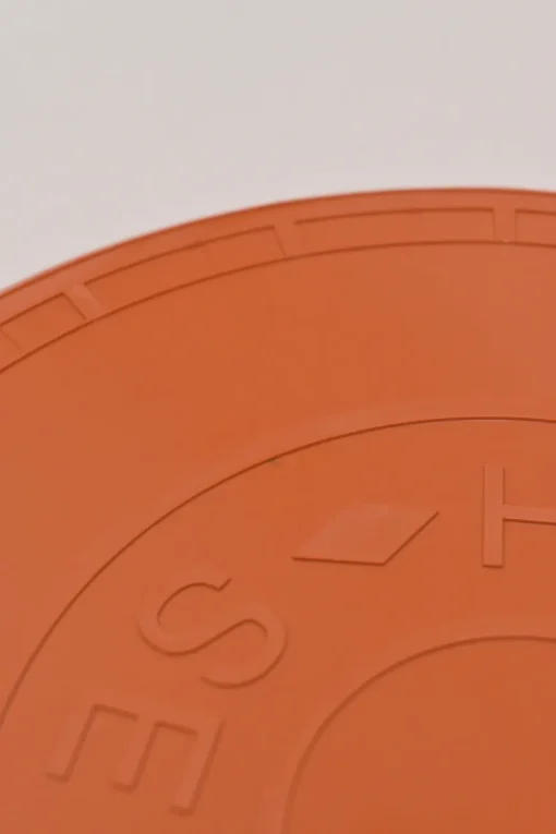 Orange plastic Wouf flying disc featuring 'Hermès Sellier Paris' embossed detail