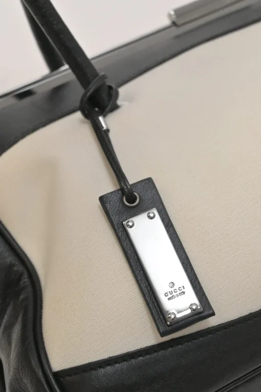 Two-tone canvas and leather frame shoulder bag with metallic push-lock closure