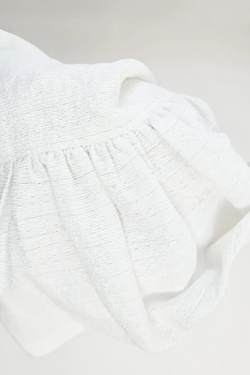 White cotton-blend textured drop-waist mini ruffle skirt with concealed rear zip fastening
