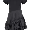 Black crew neck with folded hem short-sleeved mini dress. Adorned with layered flared pleated skirt and feature zipper closure on the side