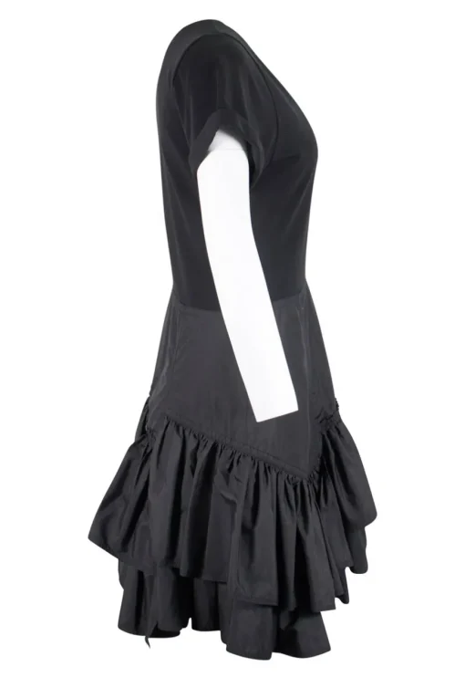 Black crew neck with folded hem short-sleeved mini dress. Adorned with layered flared pleated skirt and feature zipper closure on the side