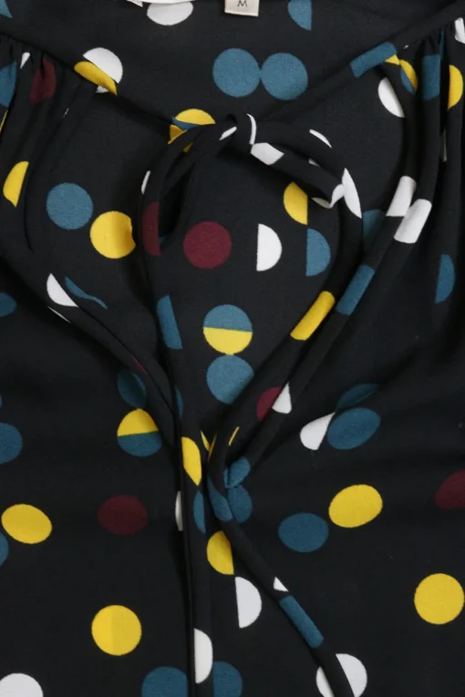 Black polyester crêpe polka dot print pullover tie neck swing-style tunic top with blouson sleeves