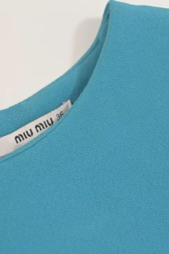 Blue long sleeve tailored blouse with chest patch, slanted hip flap pockets, and vented back