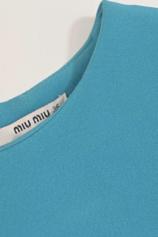 Blue long sleeve tailored blouse with chest patch, slanted hip flap pockets, and vented back