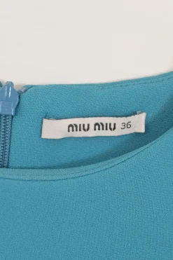 Blue long sleeve tailored blouse with chest patch, slanted hip flap pockets, and vented back