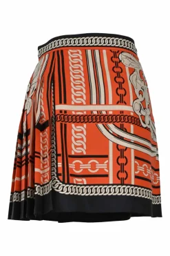 Coral and black silk chainlink foulard print apron-style pleated mini skirt with horsebit-trimmed waist