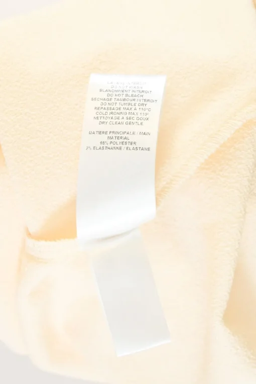 Cream draped polyester crêpe round collar bateau neck swing-style blouse with flounce cuffs