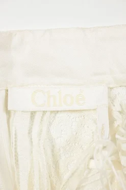 Iconic Milk viscose lace shirtwaist-style high-collar peek-a-boo peplum blouse with ribbon-tie fastening at waist