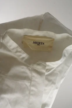 Ivory cotton poplin band collar wrap-front asymmetric apron-style shirt with self-tie fastening at waist