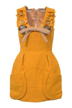 Mustard yellow bow-embellished wool pinafore mini dress featuring metallic floral appliqué and slanted hip pockets