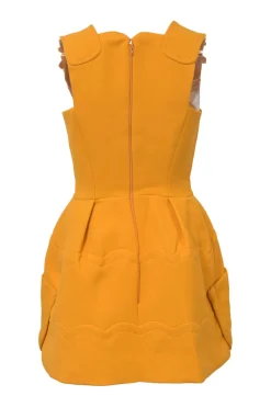 Mustard yellow bow-embellished wool pinafore mini dress featuring metallic floral appliqué and slanted hip pockets