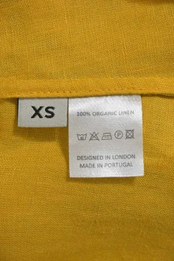 Mustard yellow draped organic linen Grecian neck swing-style shift dress with gathered neckline and self-tie fastening at nape