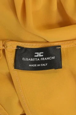 Mustard yellow polyester Bertha bib open-back ruffle blouse with draped waistband and sleeve cuffs