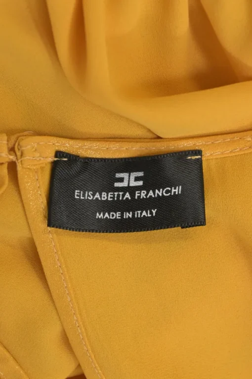 Mustard yellow polyester Bertha bib open-back ruffle blouse with draped waistband and sleeve cuffs